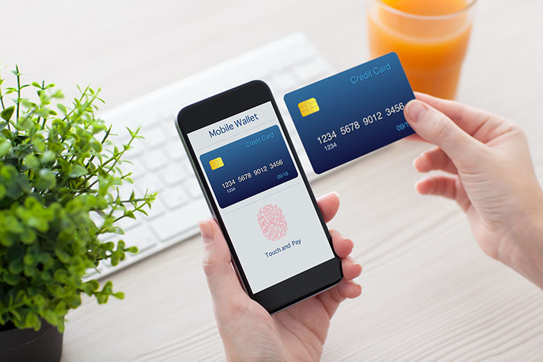 Photo of a person holding an iPhone and credit card getting ready to complete an online payment with Apple Pay.
